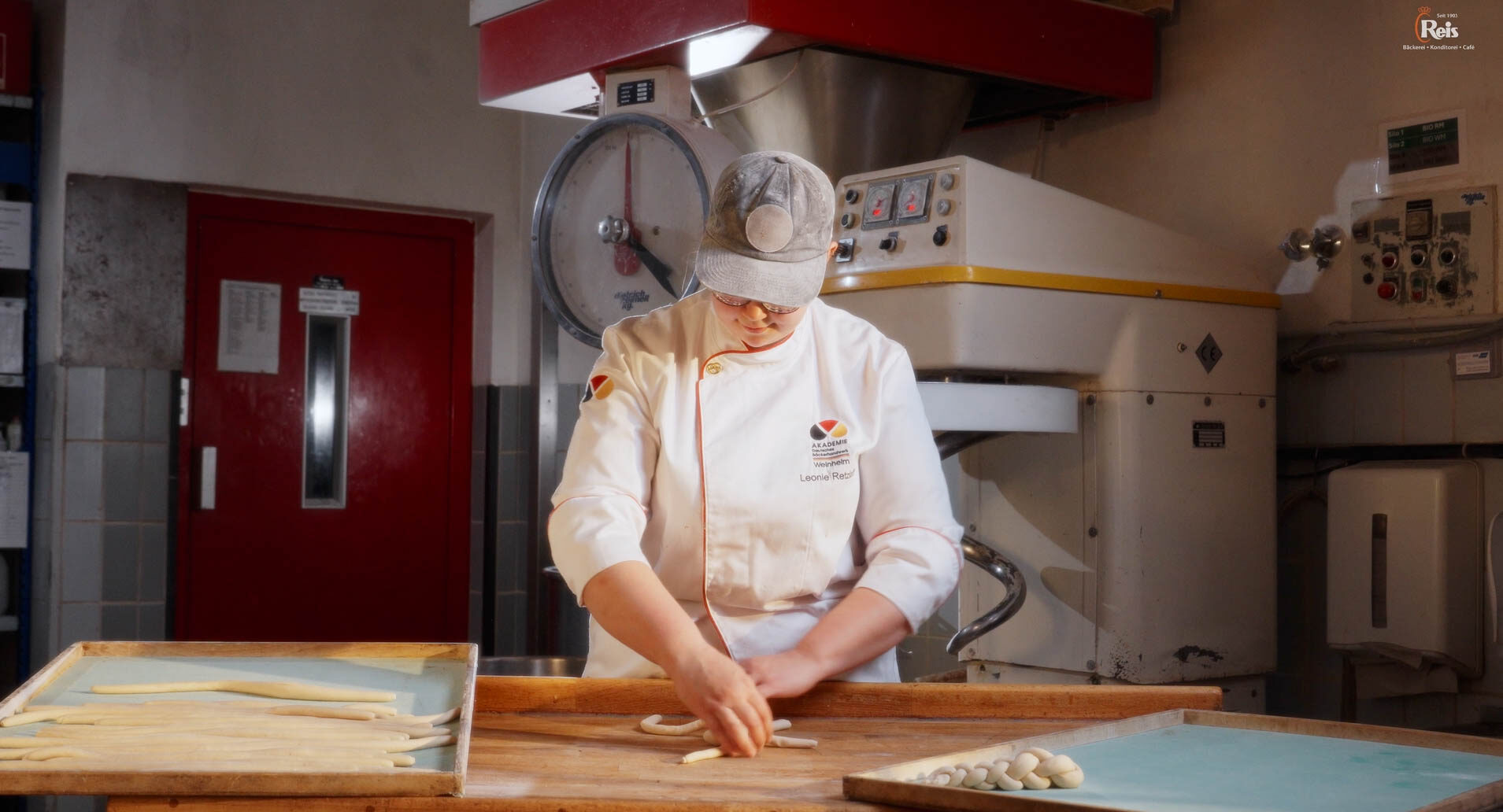 Eine Frau mit Cap und weißem Anzug flechtet einen Brezenzopf. 4kFactory hat hier ein Video erstellt.