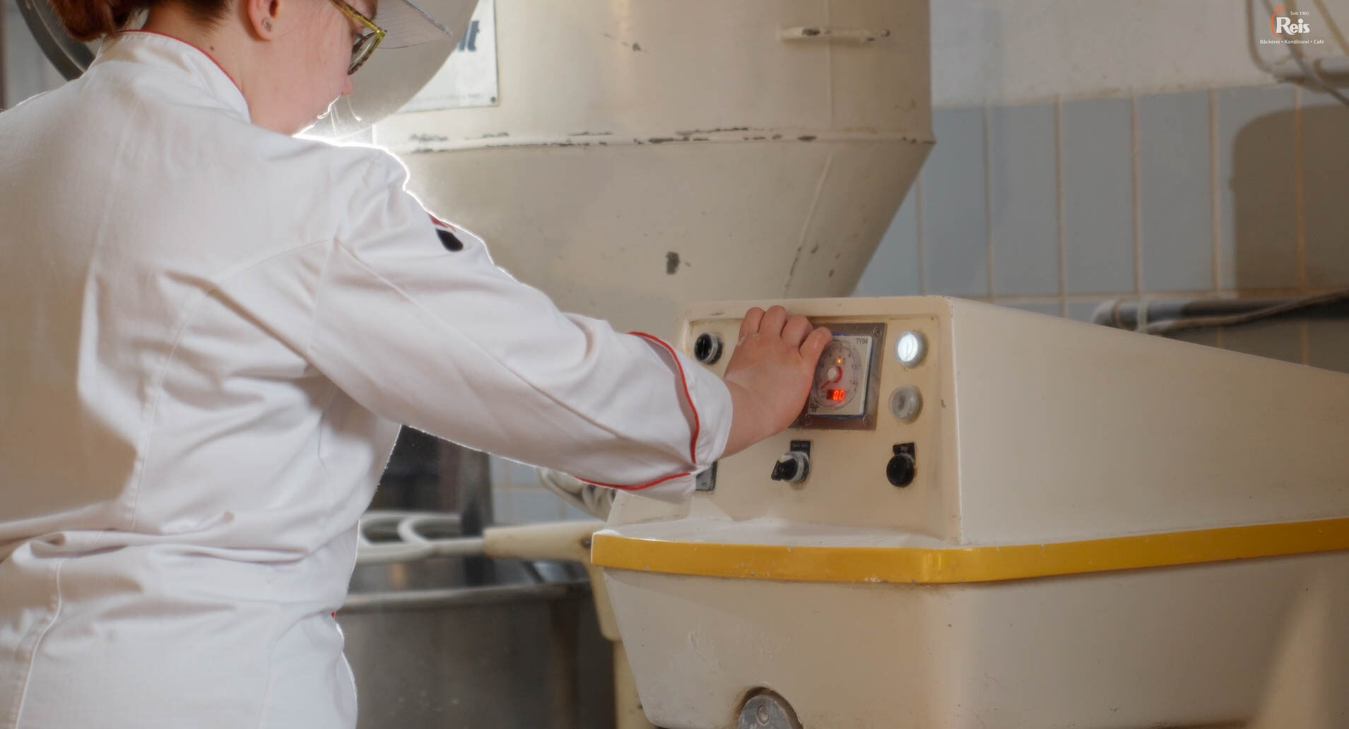 Eine Frau bedient eine Maschine. Es handelt sich um eine Knetmaschine für Teige. 4kFactory hat hier ein Video erstellt.
