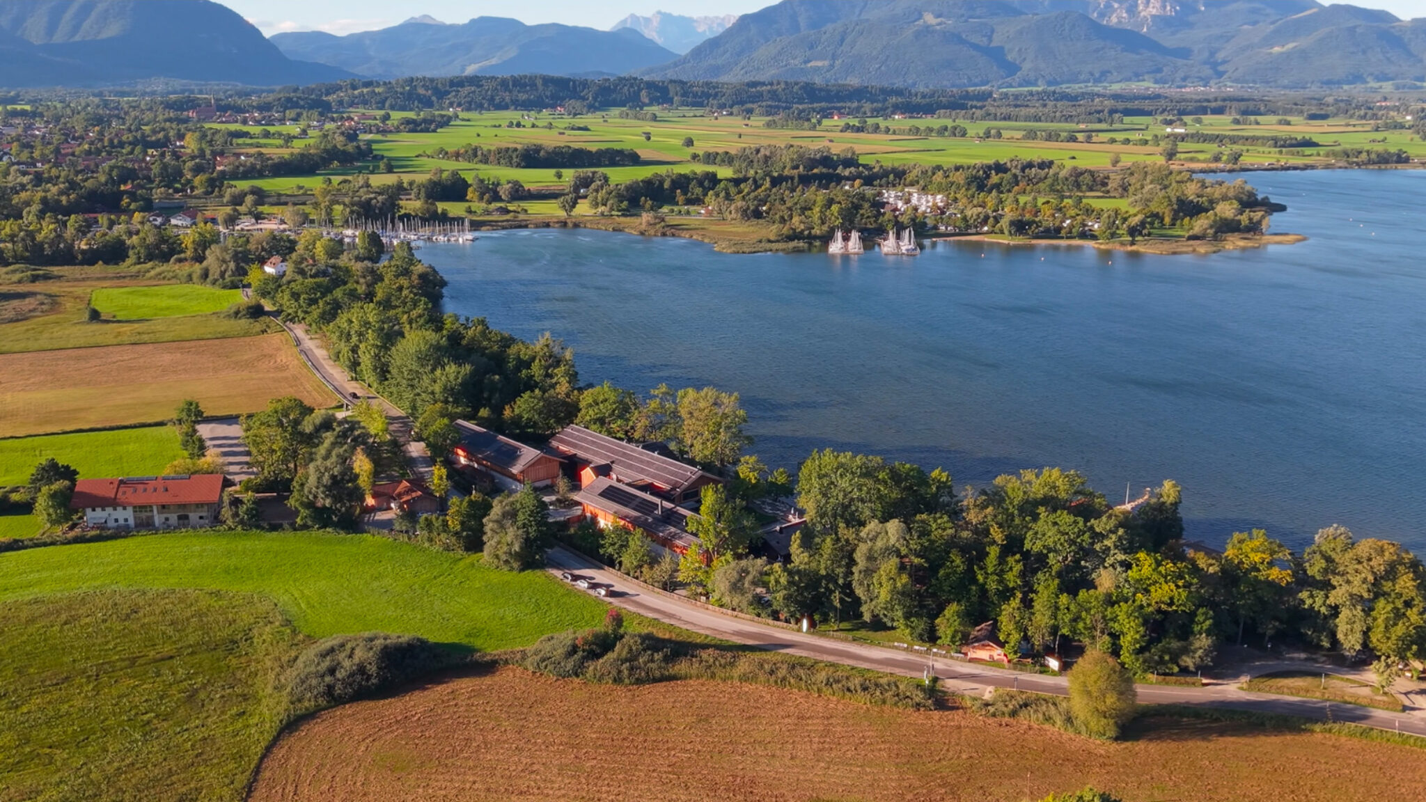 Spektakuläre Drohnenaufnahme für ein Werbevideo für Hotels von 4kFactory: Panorama-Blick auf den Chiemgauhof am Chiemsee für das 196+ Forum, eingebettet in die alpine Landschaft Oberbayerns.