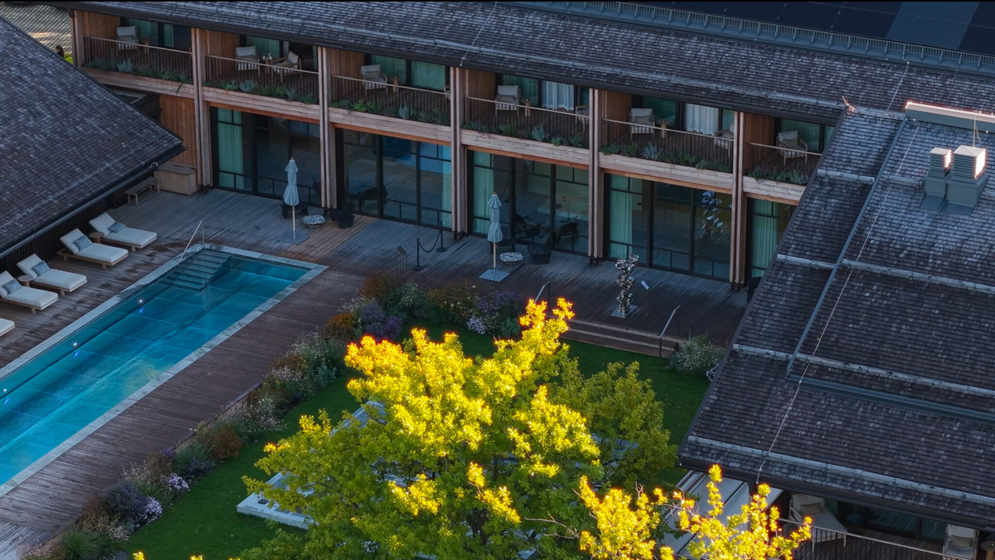 Exklusive Resort-Architektur am Chiemsee: 4kFactory zeigt eine Draufsicht auf den Poolbereich und die modernen Holzfassaden des Chiemgauhofs für das 196+ Forum.