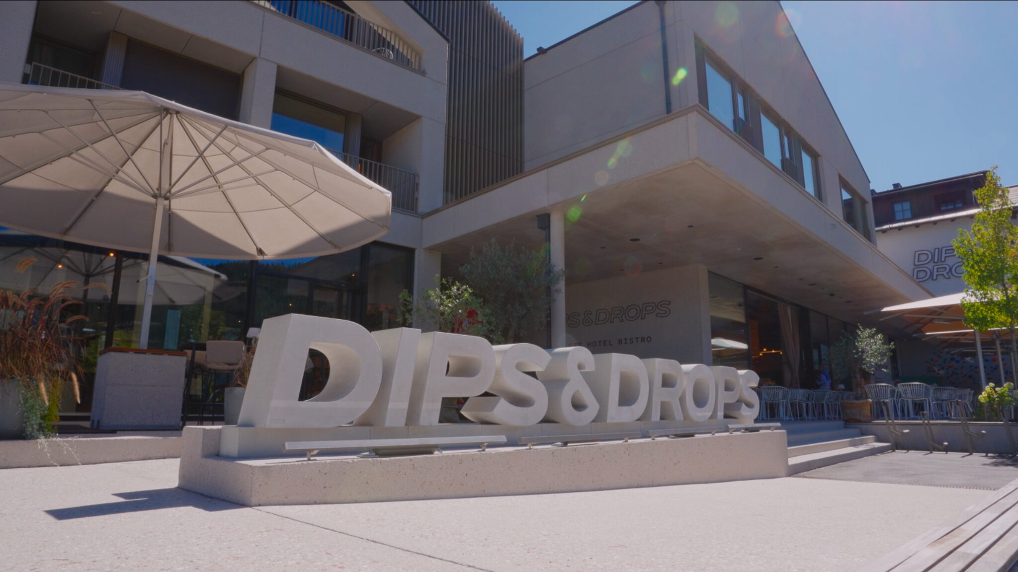 Hochwertige Branding-Inszenierung für ein Werbevideo für Hotels von 4kFactory: Der markante „Dips & Drops“ Schriftzug vor der modernen Hotel-Architektur in Flachau.