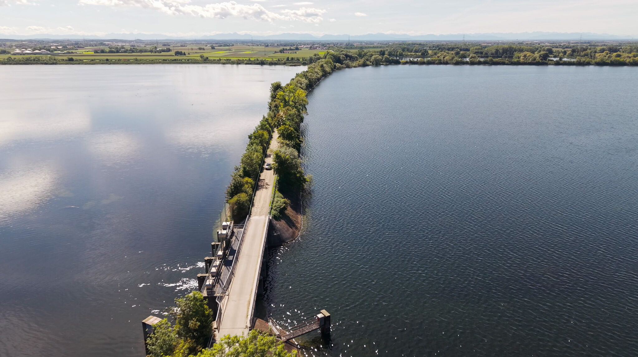 Weiträumige Luftaufnahme eines XPENG Elektroautos auf einer Straße, die durch einen See führt, als Teil einer Automotive-Videoproduktion.