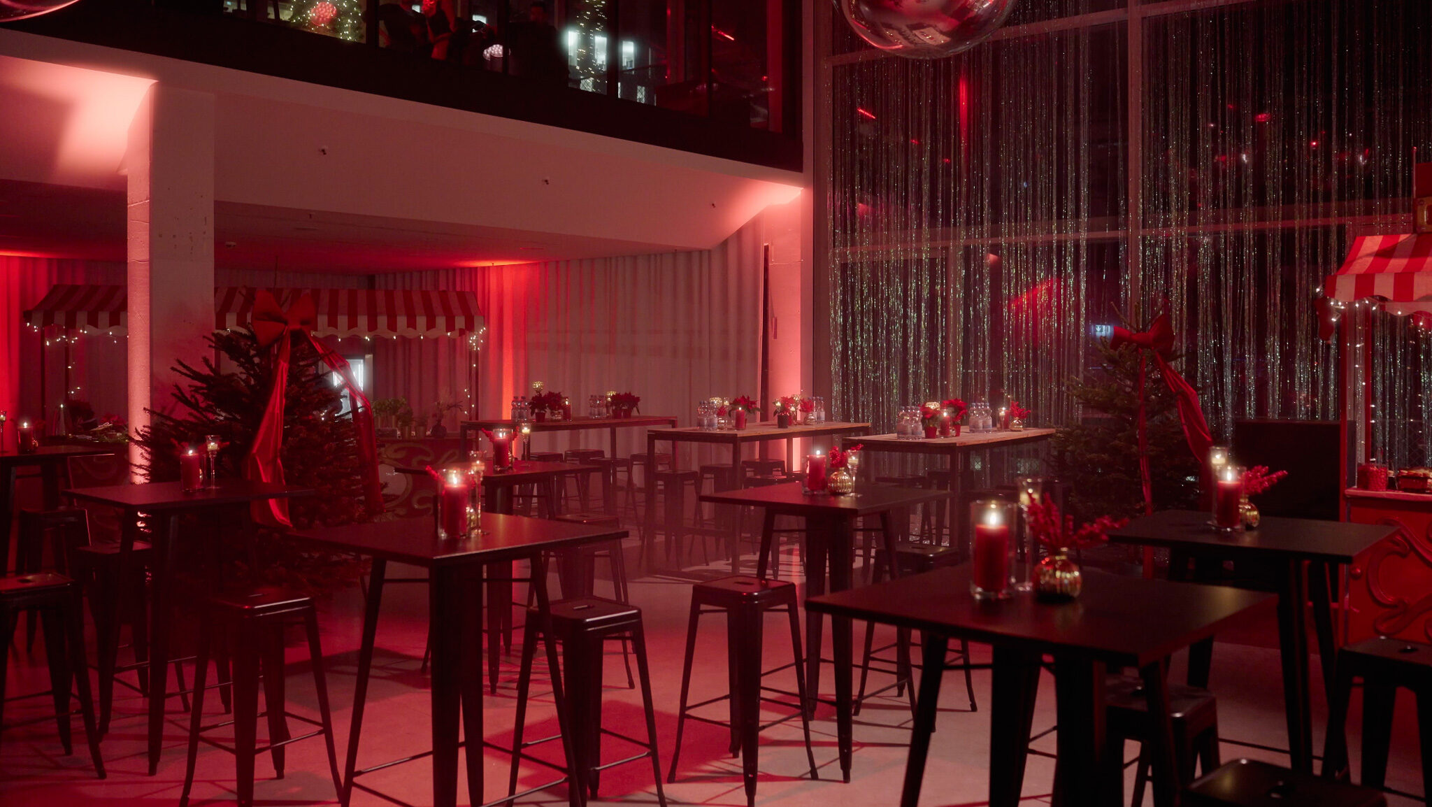 Professionelles Licht-Setup für Event-Videos der 4kFactory: Stimmungsvoll ausgeleuchteter Loungebereich bei der Avantgard Weihnachtsfeier. Die Kombination aus Kerzenschein, roten Scheinwerfern und funkelnden Vorhängen im Werk 3 München zeigt die visuelle Tiefe der 4kFactory Produktionen.