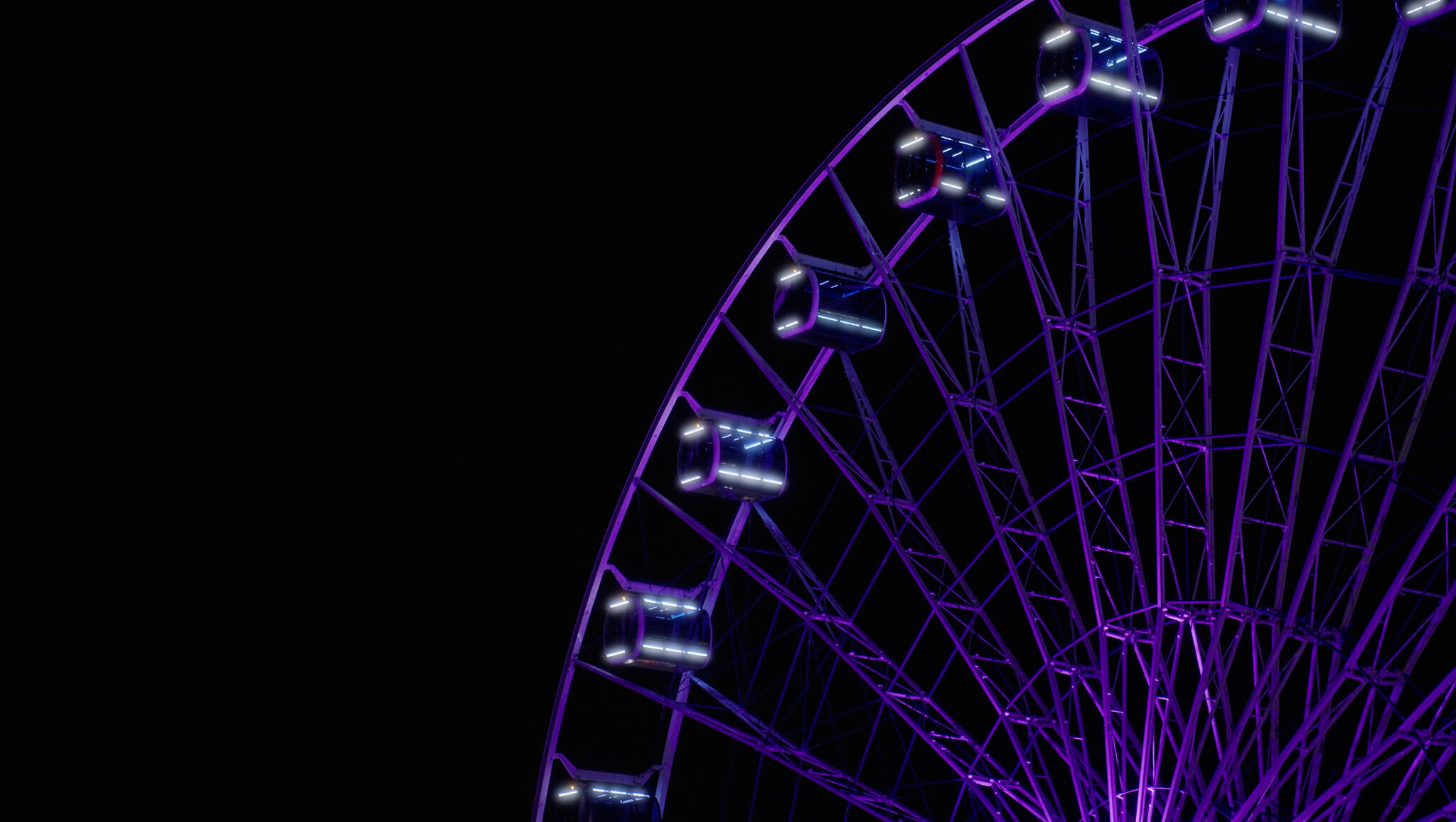 Detailaufnahme eines lila beleuchteten Riesenrads bei Nacht vor schwarzem Hintergrund – ein Highlight der Event-Videografie von 4kFactory. Die präzise Ausleuchtung der Gondeln unterstreicht die visuelle Qualität der Videoproduktion für das Avantgard Event im Werksviertel München.