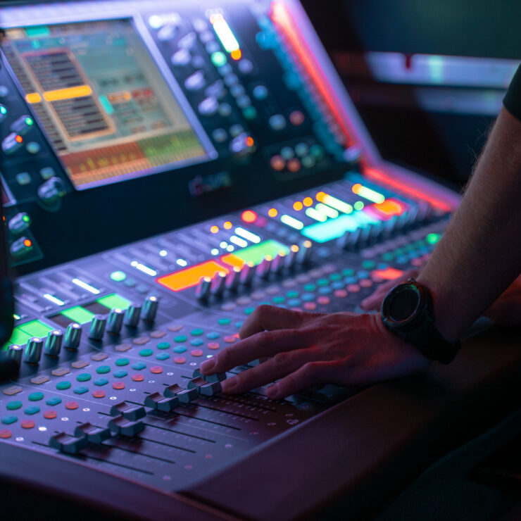 Professionelle Audio-Produktion von 4kFactory: Detailaufnahme eines Tontechnikers bei der präzisen Steuerung der Fader am Allen & Heath dLive Mischpult während des Grand Jam Events im Eintracht Frankfurt Stadion.