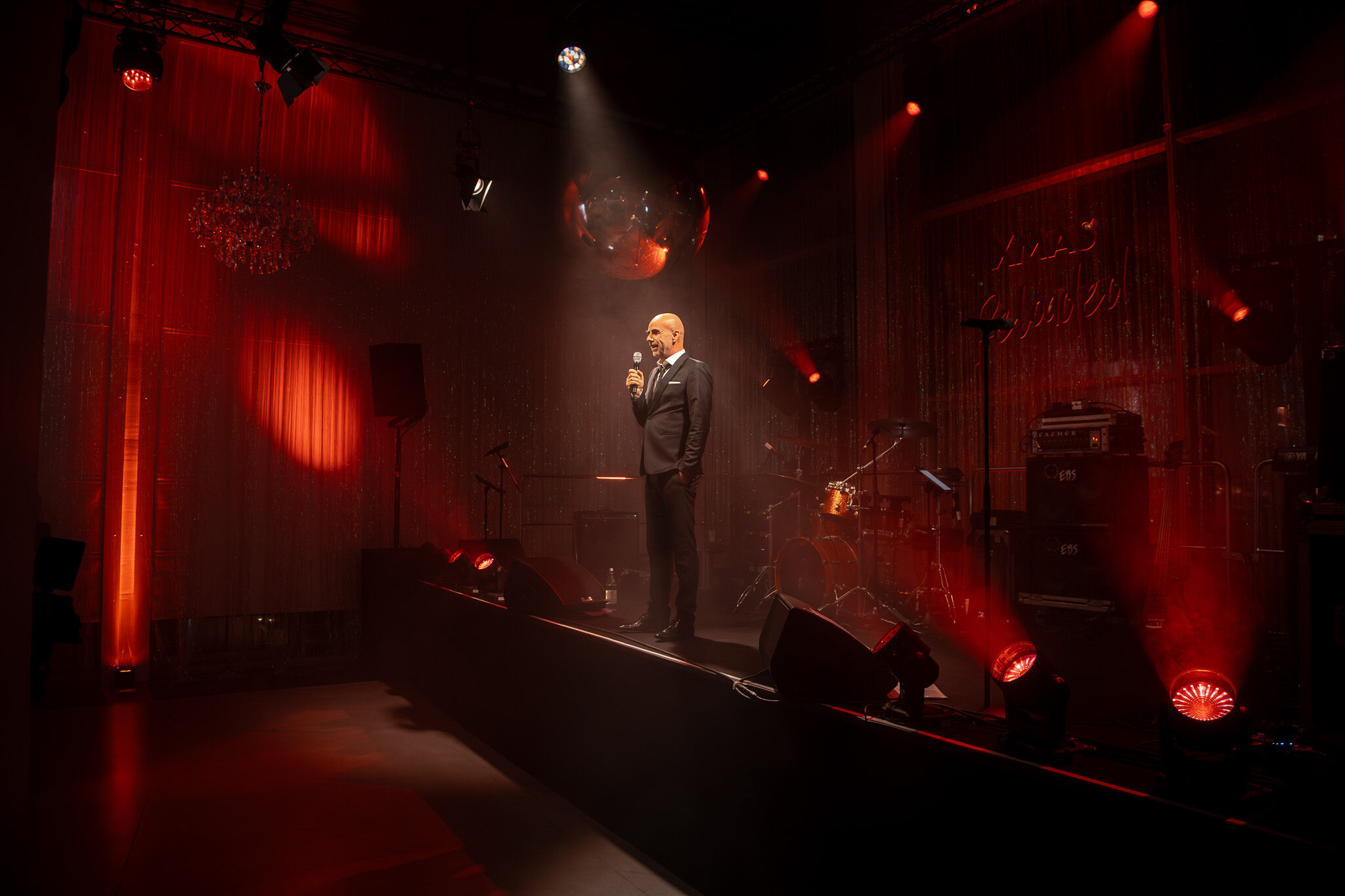 Professionelle Bühnenfotografie von 4kFactory: Keynote-Speaker bei der Avantgarde Weihnachtsfeier in München, perfekt inszeniert durch atmosphärisches Rotlicht und Spotlights.