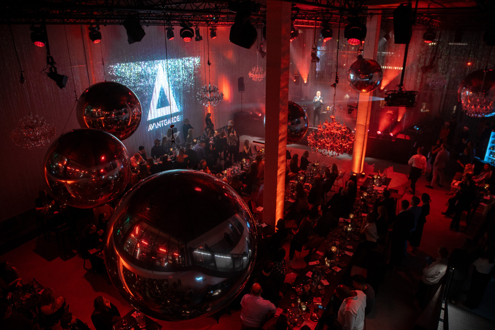 Spektakuläre Weitwinkelaufnahme von 4kFactory: Der festlich illuminierte Gala-Saal mit Diskokugeln und Avantgarde-Branding aus der Vogelperspektive.