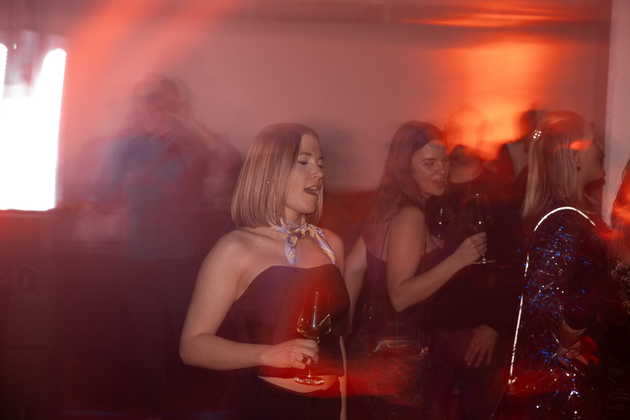 Energiegeladene Event-Fotografie von 4kFactory: Eine tanzende Frau auf der Avantgarde Weihnachtsfeier, eingefangen in stimmungsvollem Rotlicht mit künstlerischer Bewegungsunschärfe.