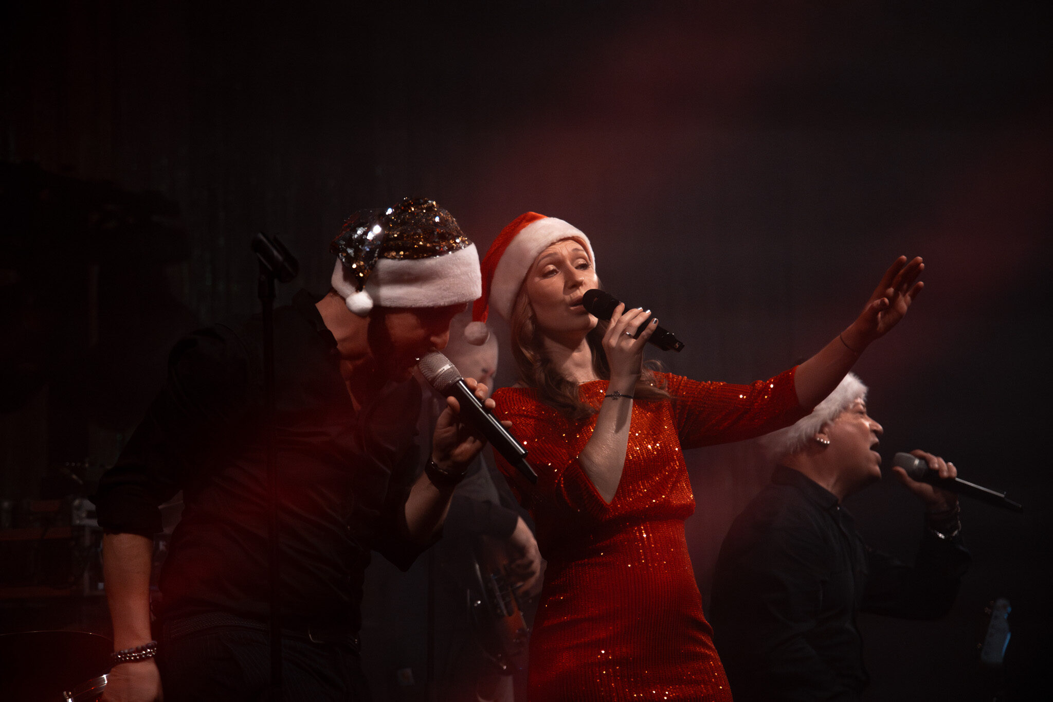 Professionelle Live-Dokumentation von 4kFactory: Ein Gesangs-Duo in festlichen Outfits und Weihnachtsmützen während der Performance auf der Avantgarde Weihnachtsfeier in München.