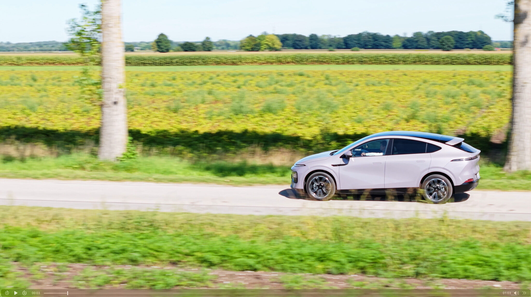 „Seitenprofil eines weißen XPENG G6 in Fahrt auf einer Landstraße, aufgenommen mit einer Tracking-Kamera für eine Automotive-Videoproduktion.“