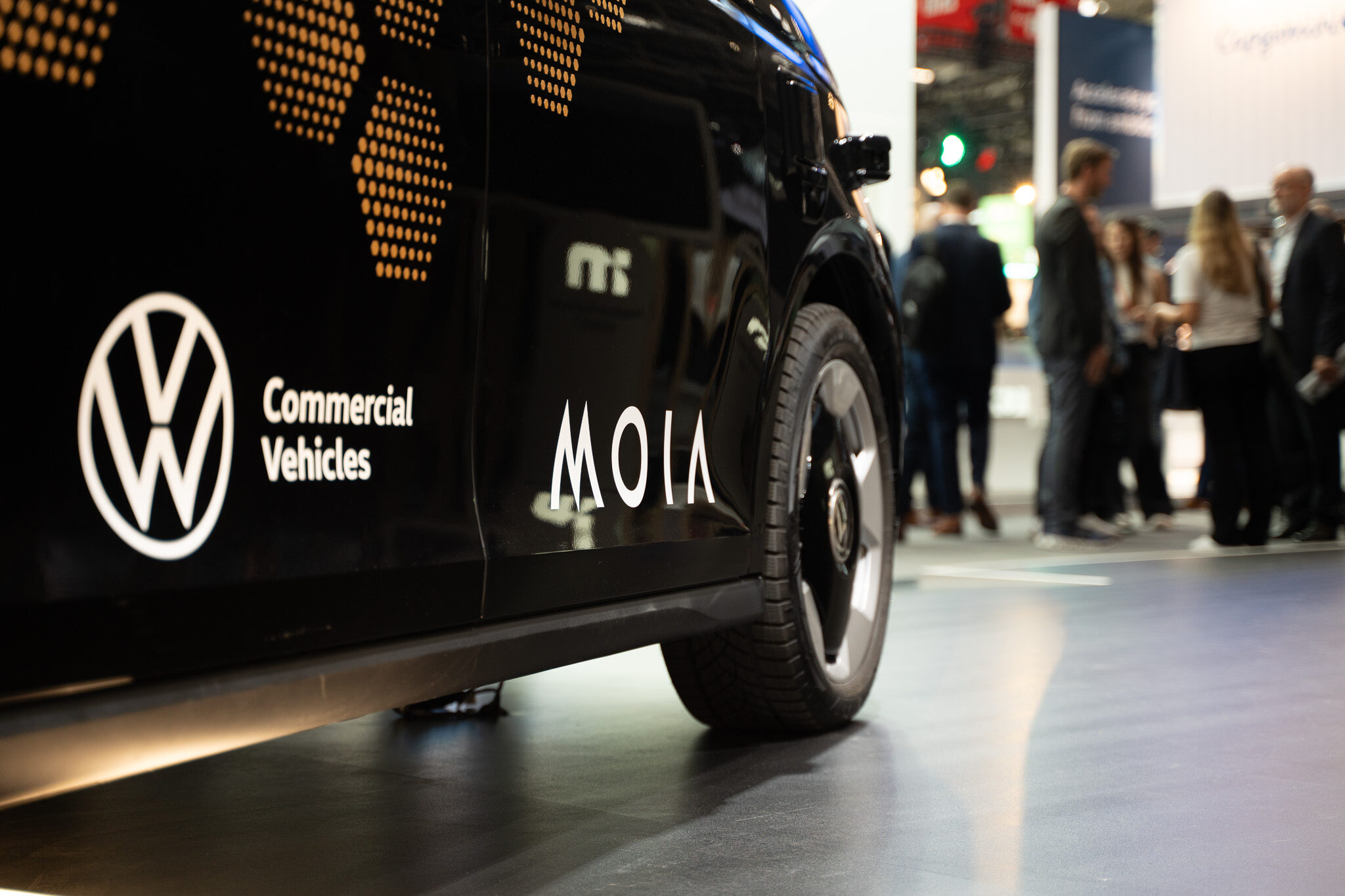 „Zukunft der Mobilität im Rampenlicht: Das autonome MOIA-Fahrzeug (Volkswagen ID. Buzz AD) präsentiert auf dem Mobileye-Stand der IAA MOBILITY. Die Aufnahme von 4kFactory zeigt das markante Design mit goldenem Wabenmuster und integrierter Sensortechnik vor einer dynamischen LED-Kulisse.“