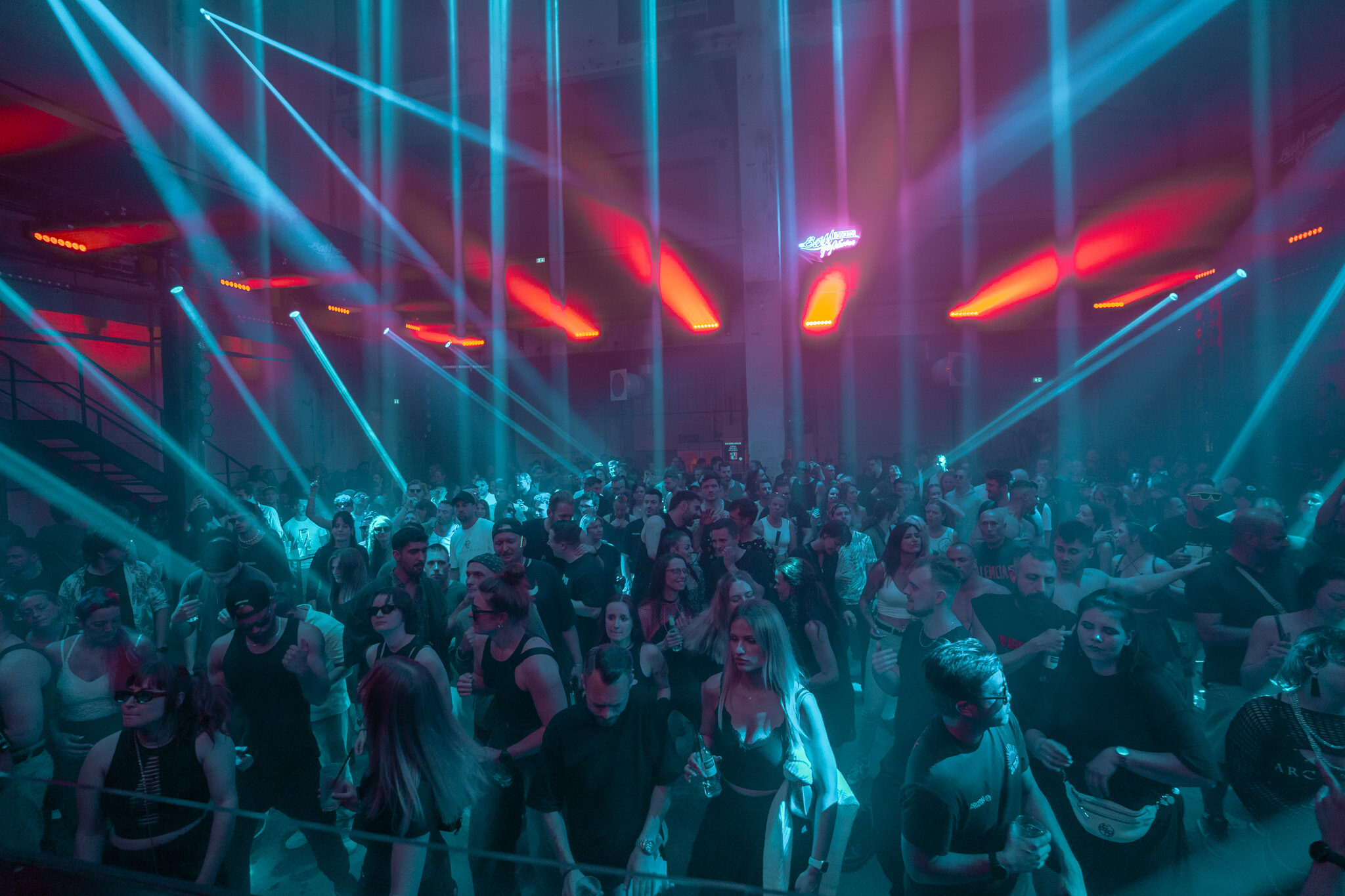 Immersive Event-Fotografie von 4kFactory: Eine tanzende Menge im Kesselhaus Nürnberg während eines Bassgeflüster-Events, inszeniert durch ein komplexes Laser- und Lichtdesign.