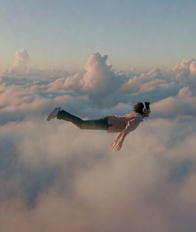 Ein Mann fliegt durch die Wolken und hat dabei Kopfhörer auf.